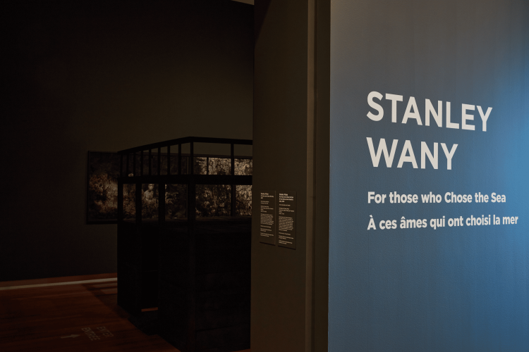 Stanley Wany, For those who Chose the Sea, 2022, Mixed media installation, dimensions variable. Includes: 3 x mixed-media illustration/painting on Strathmore paper, 100.6 cm x 152.4 cm (each); video edited by Stanley Wany, footage captured by Frederick Murphy, 15 minutes; wooden structure: Peter Shmelzer. Courtesy of the artist, and supported by the Canada Council for the Arts. Installation at the Ottawa Art Gallery, 2022. Photo: Rémi Thériault